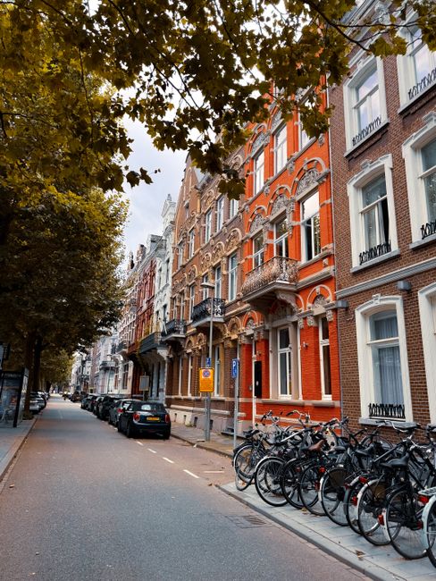 A large Mercedes-Benz moving truck with a white, red, and yellow exterior is positioned on a narrow cobbled street in Holland Park, surrounded by typical Victorian-style terraced residential buildings